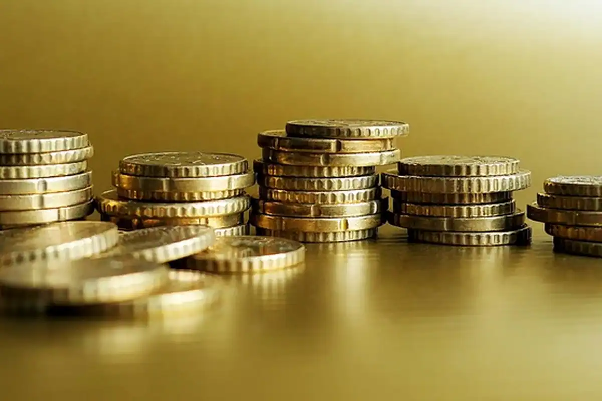 Stive de monede aurii pe o suprafață lucioasă, simbol pentru capitalul unei firme