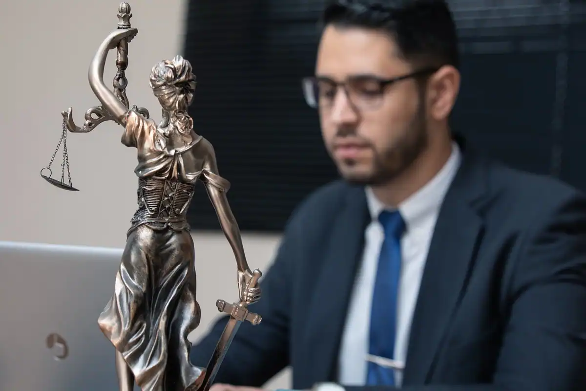 Un avocat lucrează la birou, lângă o statuetă a Justiției