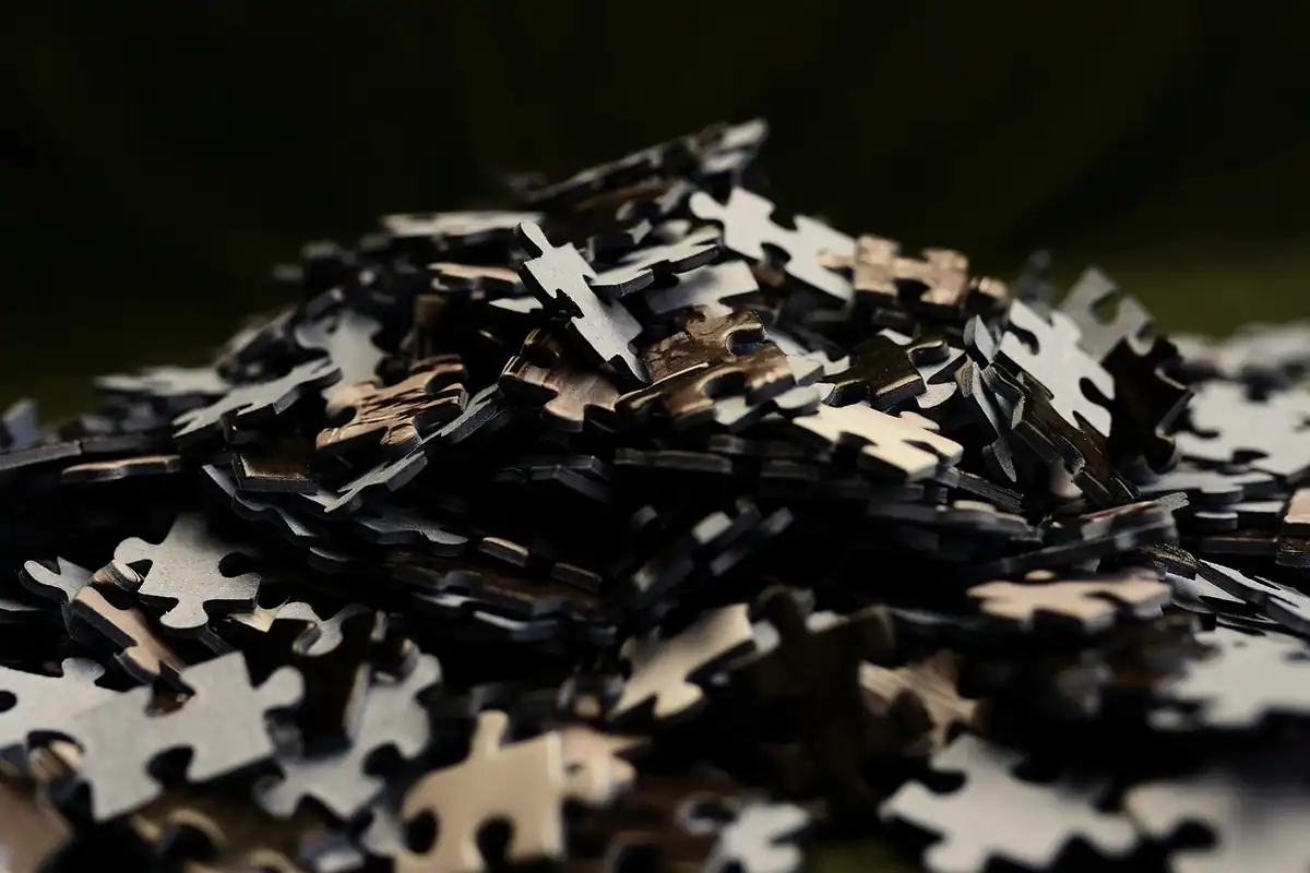 Morman de piese de puzzle, risipite pe o masă întunecată