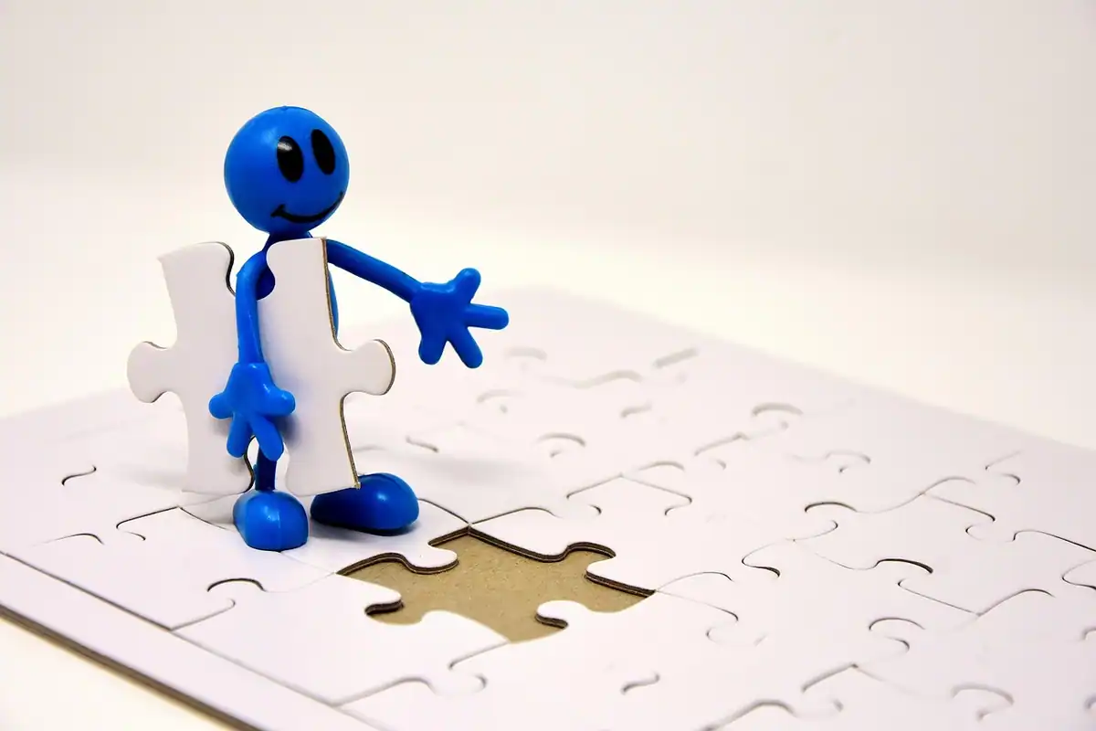 Figurină albastră lângă o piesă de puzzle care lipsește dintr-un joc alb