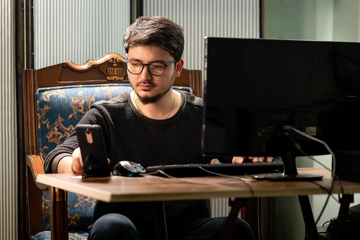 Un bărbat completează date pe calculator, așezat la birou într-un fotoliu vechi