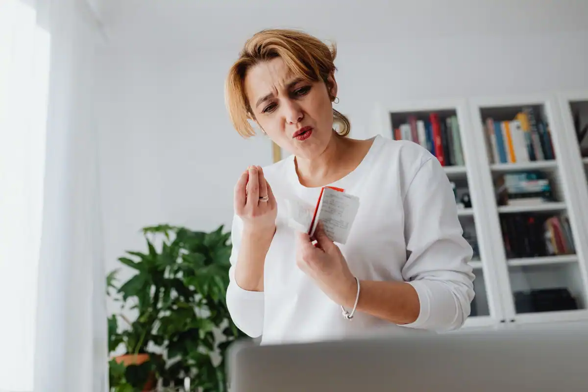 O femeie încruntată privește un card, într-o cameră cu rafturi cu cărți