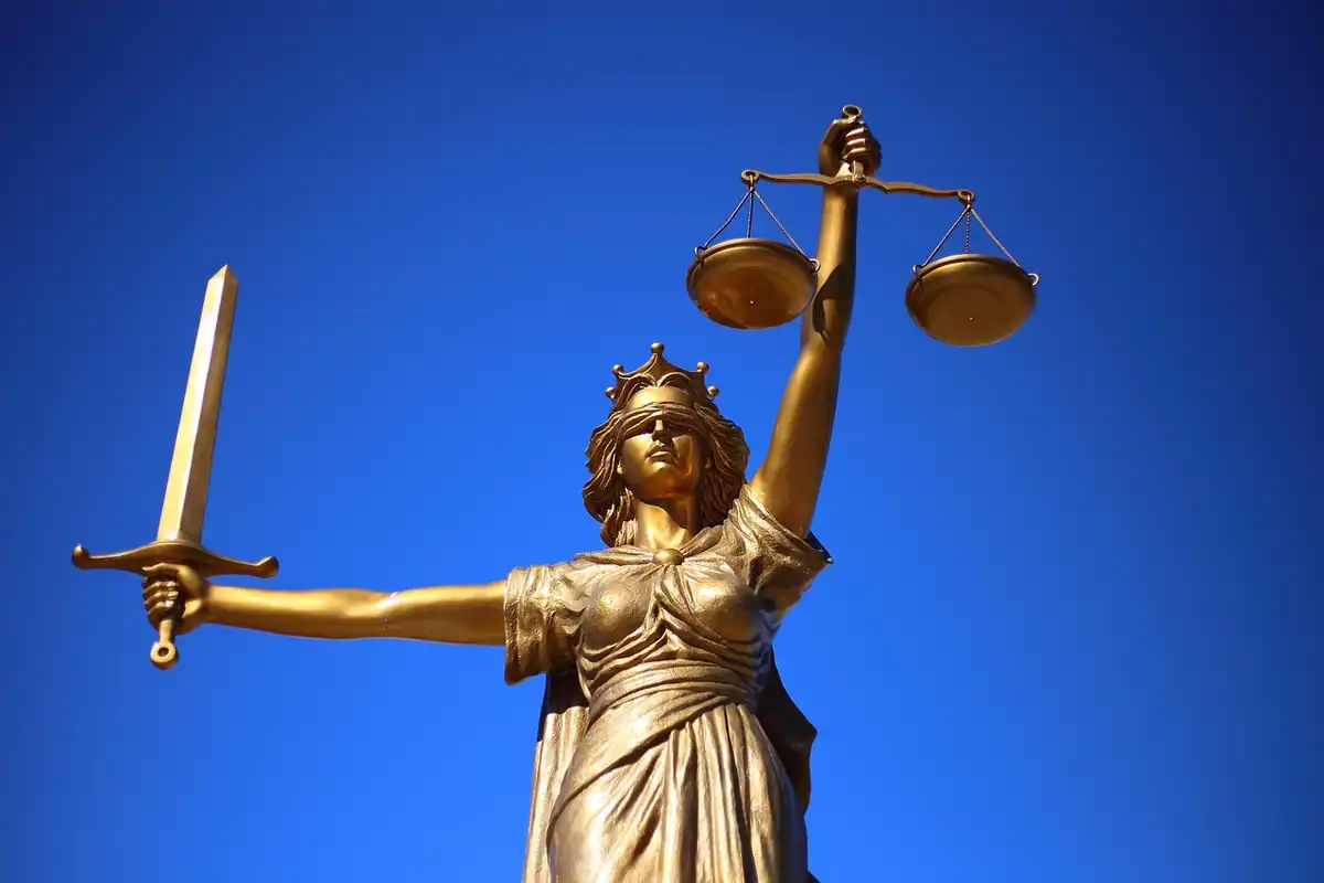 Statuia Justiției cu sabie și balanță, pe fundal de cer albastru