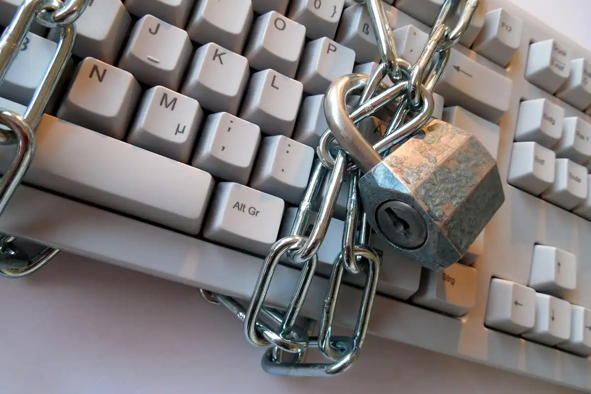 Lanț și lacăt prinse peste o tastatură, simbol al protecției datelor