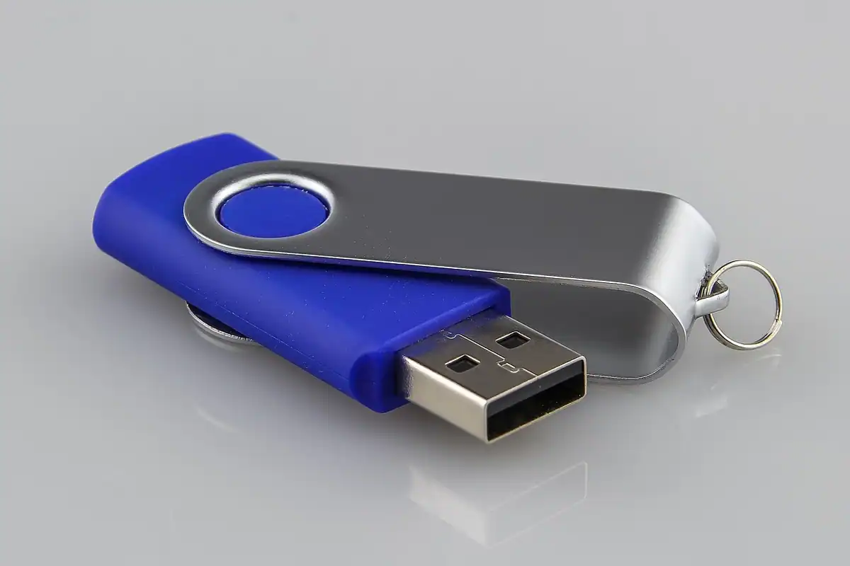 Stick USB albastru, cu carcasă metalică, pe un fundal gri deschis