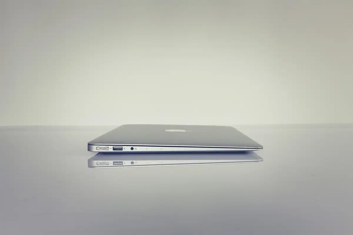 Laptop închis, așezat pe o masă netedă, pe un fundal gri